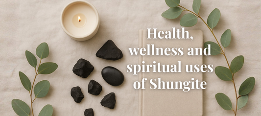 Soft, serene flat lay featuring Shungite stones beside a candle, journal, and eucalyptus leaves on a linen background.